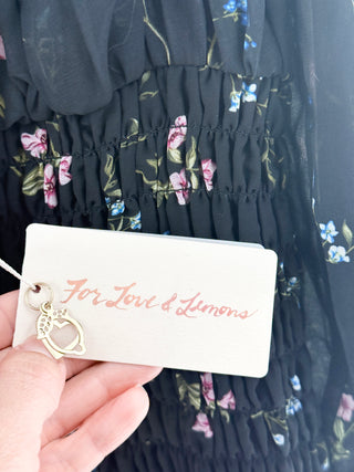 For Love & Lemons Dixon mini dress featuring sheer chiffon overlay with floral print throughout, designed with fully smocked body, sweetheart neckline, sheer puff sleeves, and ruffled hem, M