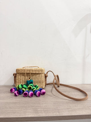 Nannacay small straw bag with pom pom charms and long strap