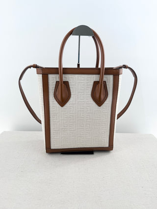 Balmain logo tote bag crafted from jacquard canvas featuring signature tonal monogram pattern, accented with smooth cognac leather trim, dual rolled top handles and detachable shoulder strap