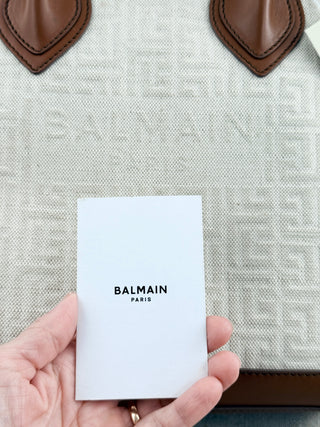 Balmain logo tote bag crafted from jacquard canvas featuring signature tonal monogram pattern, accented with smooth cognac leather trim, dual rolled top handles and detachable shoulder strap