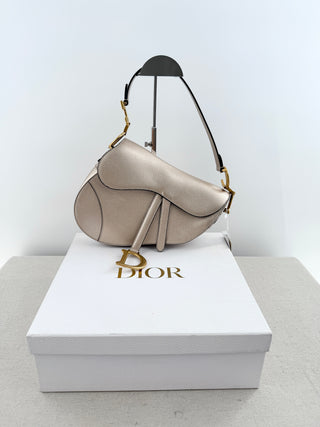 Christian Dior saddle bag crafted in grained calfskin leather featuring asymmetrical saddle silhouette, front flap closure, and oversized antique "D" charm