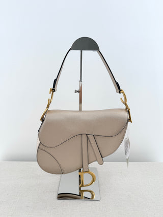 Christian Dior saddle bag crafted in grained calfskin leather featuring asymmetrical saddle silhouette, front flap closure, and oversized antique "D" charm