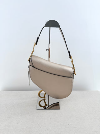 Christian Dior saddle bag crafted in grained calfskin leather featuring asymmetrical saddle silhouette, front flap closure, and oversized antique "D" charm