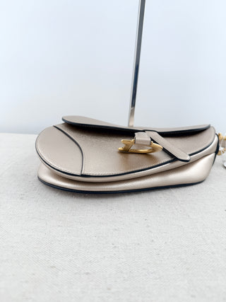 Christian Dior saddle bag crafted in grained calfskin leather featuring asymmetrical saddle silhouette, front flap closure, and oversized antique "D" charm