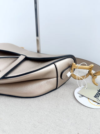 Christian Dior saddle bag crafted in grained calfskin leather featuring asymmetrical saddle silhouette, front flap closure, and oversized antique "D" charm