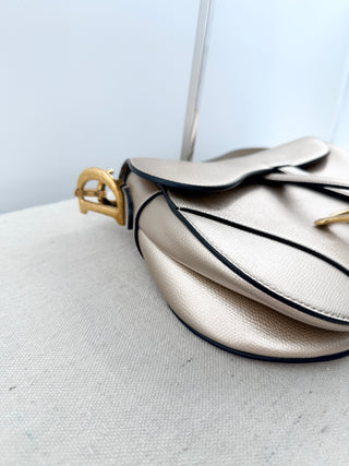 Christian Dior saddle bag crafted in grained calfskin leather featuring asymmetrical saddle silhouette, front flap closure, and oversized antique "D" charm