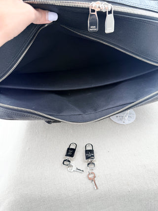Louis Vuitton briefcase crafted in signature taiga leather featuring top zip closure, front slip pocket, and rolled leather handles